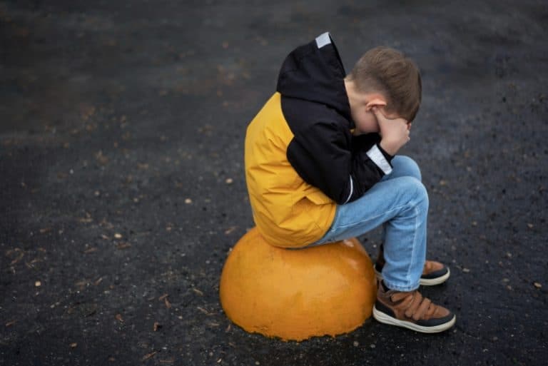 Copil ținut cu mâinile la spate și obligat de o femeie să lingă un gard de lemn, minute în șir