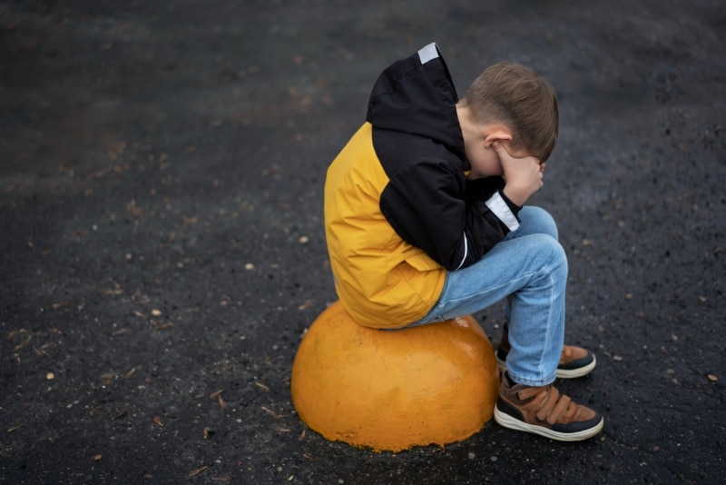 Copil ținut cu mâinile la spate și obligat de o femeie să lingă un gard de lemn, minute în șir